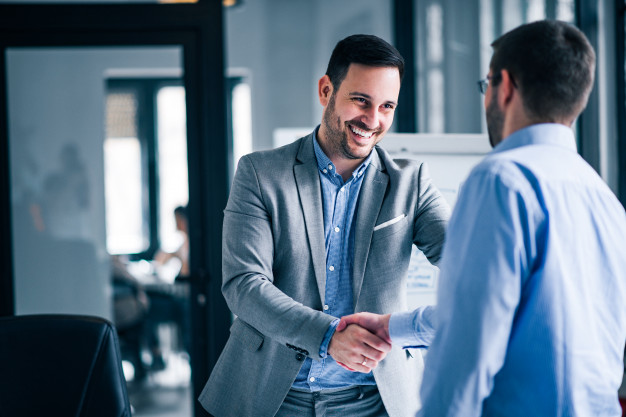 two-smiling-businessmen-shaking-hands-while-standing-office_109710-1799